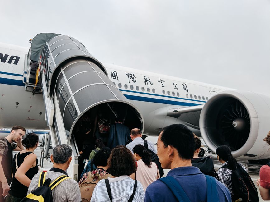 A group of travellers with hand luggage boarding an aircraft from the tarmac