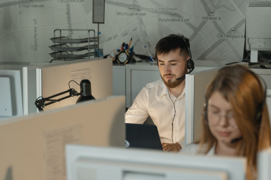 Two support staff wearing headsets handling calls in an office